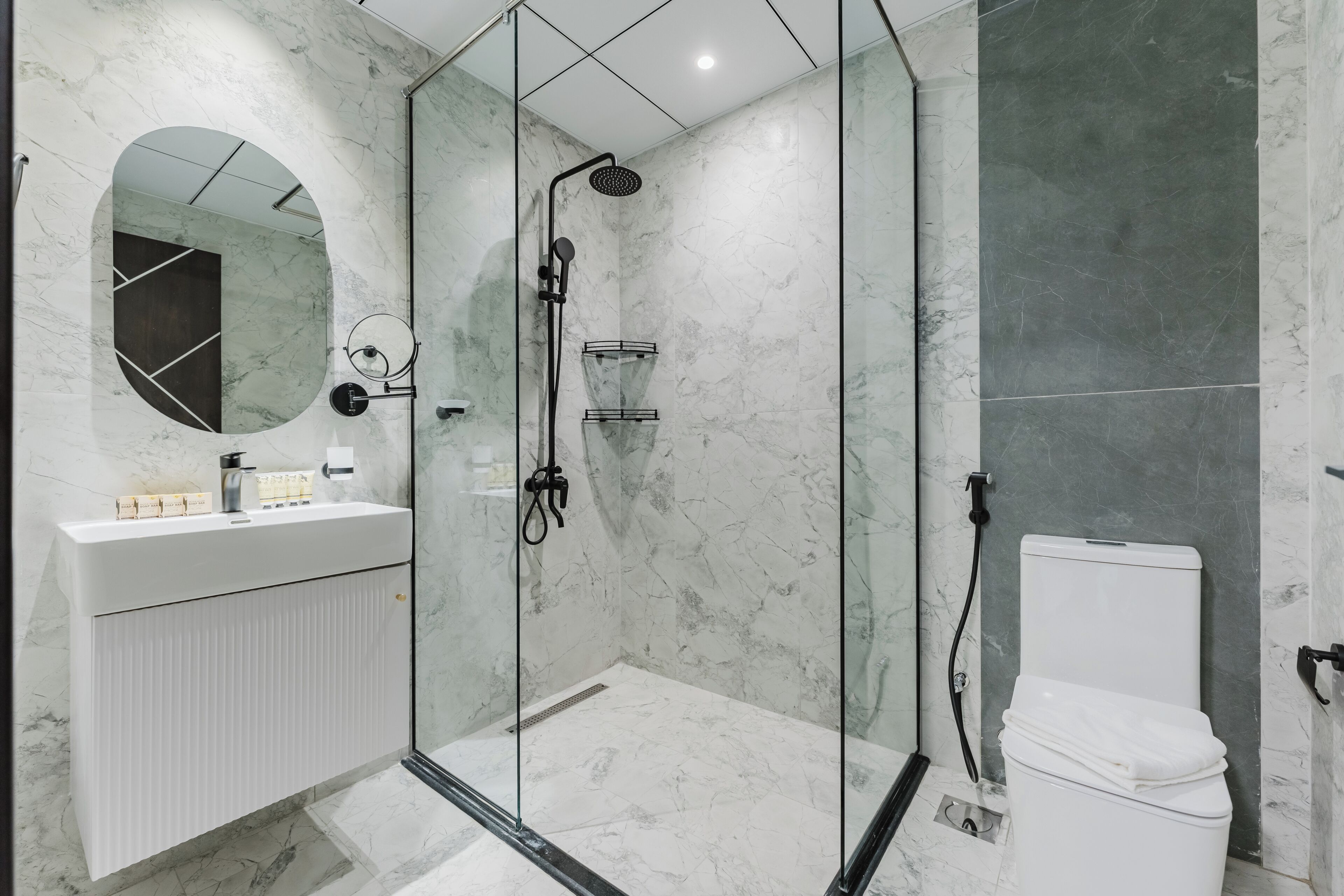 Un bagno moderno con doccia vetrata, lavandino bianco con specchio e servizi igienici.