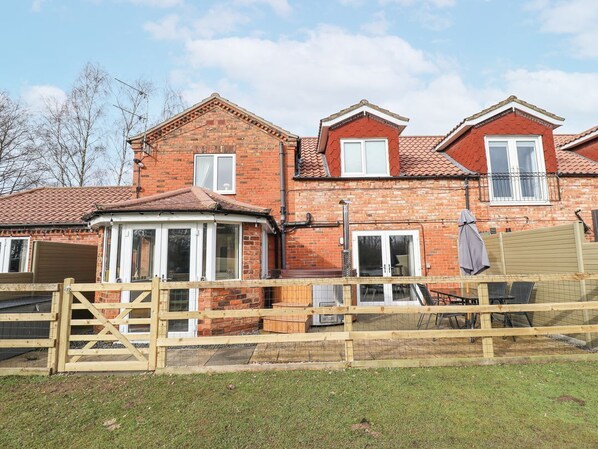 A two-story brick house with a gated entrance, a covered porch, and a small patio area.