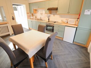 A compact kitchen with a dining table, chairs, a microwave, stove, and cabinets.