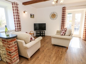 A living room with two sofas, a TV, a clock, and a fireplace. - Stable Cottage, Gatcombe (Newport)