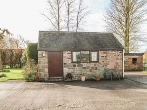 A small stone building with a dark brown door, windows, and a paved driveway. - Cordwainer Cottage, Cayton (Stoke-on-Trent)