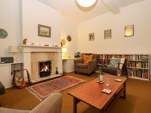 Un salon avec une cheminée, un canapé, une table basse et une bibliothèque.