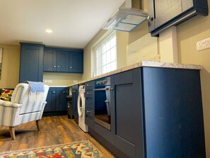 Una cocina con armarios azules, horno empotrado y lavadora.