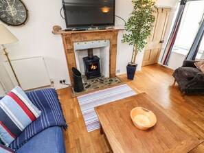 A cozy living room with a fireplace, a television, a sofa, and a dining table. - Labour in Vain, St Ives (St. Ives)