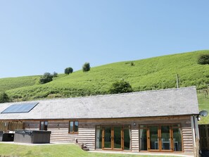Eine Holzhütte mit geneigtem Dach, großen Glasüren und einer Solarzelle.