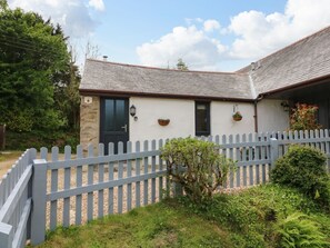 A building with a stone facade, a black door, and a white picket fence. - Ash Cottage, Combe Martin (Ilfracombe)
