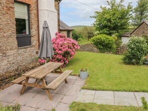 A stone building with a wooden picnic table and a potted plant. - Ash Cottage, Combe Martin (Ilfracombe)