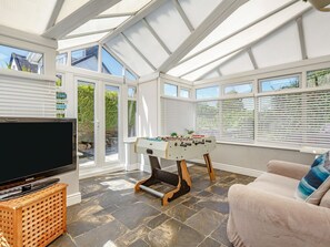 A sunlit room with a foosball table, a television, and a sofa. - BRYN RHOSYN, WiFi, Pet-friendly, En-suite, Nefyn (Pwllheli)