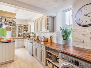 A kitchen with white cabinetry, a wooden countertop, a clock, and a washing machine. - BRYN RHOSYN, WiFi, Pet-friendly, En-suite, Nefyn (Pwllheli)