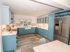 Una cocina moderna con armarios azul claro, electrodomésticos de acero inoxidable y suelo de madera.