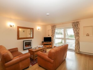 A living room with a sofa, a TV, a fireplace, and a large window with curtains.