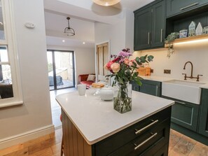 A modern kitchen with dark green cabinets, a white countertop, and a vase with flowers. - 26 Frenchgate, Richmond (Gateway)