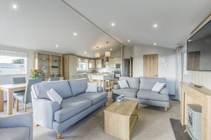Un salon moderne avec deux canapés, une table basse et, au fond, un espace cuisine.