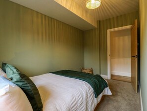 A bedroom with a bed, a door, and a ceiling light fixture.