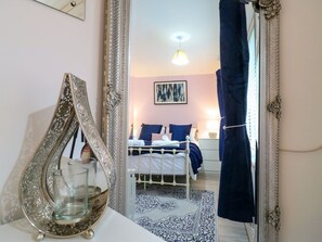 Ein Schlafzimmer mit Bett, Nachttisch und einem Spiegel, der den Raum reflektiert.