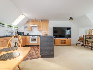 Eine moderne Küche mit Holzausstattung, einer zentralen Kochinsel und einem Essbereich mit Tisch und Stühlen.
