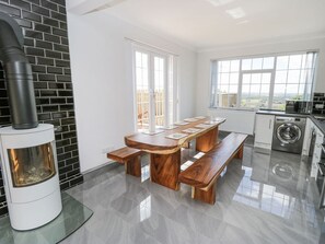 Una cocina moderna con estufa integrada, una mesa de comedor con bancos, lavadora y ventanas amplias.
