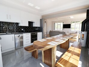 Una cocina moderna con armarios blancos, una mesa grande de madera y una estufa negra.