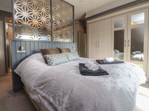Ein Schlafzimmer mit einem großen Bett, einem Kleiderschrank und einer dekorativen Wandverkleidung.