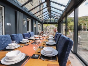 Ein Essbereich mit Glasdecke, blau gepolsterten Stühlen und einem Tisch, der für eine Mahlzeit gedeckt ist.