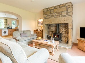 Ein Wohnzimmer mit Kamin aus Stein, einer Couch, einem Couchtisch und einem Fernseher.