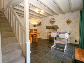 A room with a stone wall, a foosball table, a wooden staircase, and a dining table. - 2 Banc Llugwy, Betws-Y-Coed (Betws-y-Coed)
