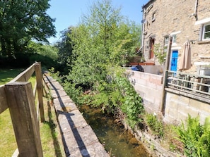 A stone building with a blue door, a wooden fence, and a narrow water channel.