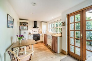 A kitchen with white cabinets, a wooden table, and a window with curtains. - 2 Beacon High, Lindale (Grange-Over-Sands)