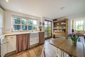 A kitchen with a wooden table, white cabinets, and a window overlooking greenery. - 2 Beacon High, Lindale (Grange-Over-Sands)