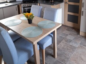 A dining table with placemats, chairs, and a potted plant.