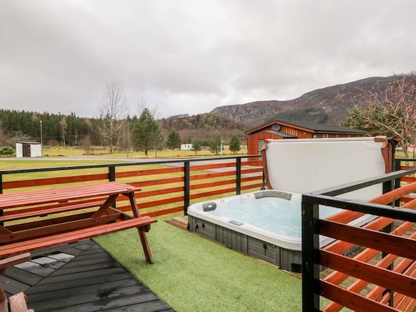 Ein Whirlpool, eine Holzterrasse und eine Bergblick.
