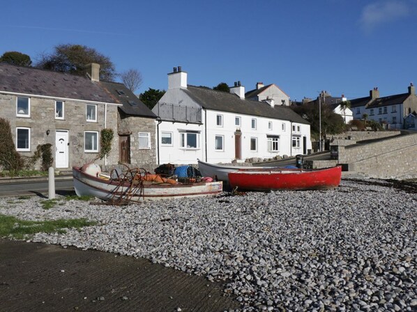 A row of stone buildings with a pebbled beach in front. - Vista - Stunning Views in Moelfre (Moelfre)