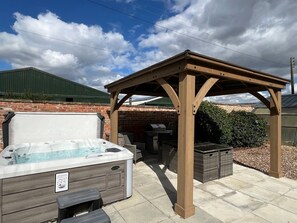 A hot tub under a wooden pergola, a brick wall, and a grill area. - Moortown House, Caistor (Market Rasen)