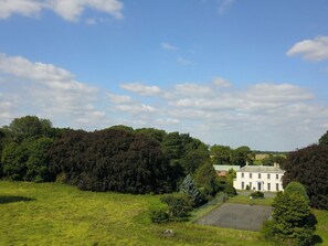 A large, white building with a green roof, surrounded by lush greenery and a clear sky. - Moortown House, Caistor (Market Rasen)