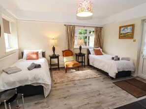 A room with two beds, a chair, a lamp, a window with curtains, and a door. - Moortown House, Caistor (Market Rasen)