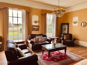 Ein Wohnzimmer mit Ledersofas, einem Glastisch und einer Chandelüster.