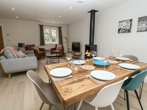 Ein modernes Wohnzimmer mit Kamin, Esstisch für vier Personen und einer Couch.