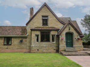 A stone house with a green door, a small window, and a chimney. - Keepers Cottage is in Shobdon. (Leominster)