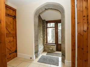 An interior hallway with a stone archway, wooden doors, and a window. - Keepers Cottage is in Shobdon. (Leominster)