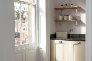 A kitchen with white cabinets, a black countertop, and wooden shelves with kitchen items. - Milldale: A Charming Home in Ashbourne (Ashbourne)