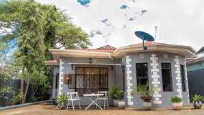 A modern house with a satellite dish, a patio with a table and chairs, and potted plants. - Peaceful 2-bedroom house in charming Arusha for your getaway (Arusha)