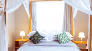 A four-poster canopy bed with two bedside tables, each with a lamp. - Peaceful 2-bedroom house in charming Arusha for your getaway (Arusha)