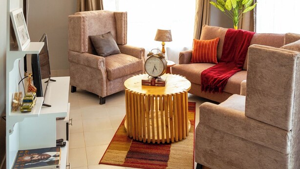 A living room with a sofa, armchairs, a coffee table, a side table, and a plant. - Peaceful 2-bedroom house in charming Arusha for your getaway (Arusha)