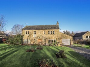 A stone house with a large front lawn, a garage, and a well-maintained garden. - Orchard House, West Witton (Leyburn)
