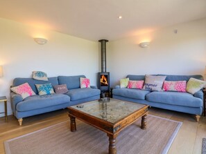 Ein Wohnzimmer mit zwei Sofas, einem Glastisch und einem Kaminofen.