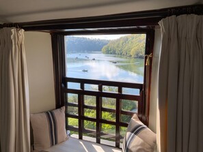 Ein Fenster mit Blick auf einen See und Boote, ein Holgitter und ein Kissen.