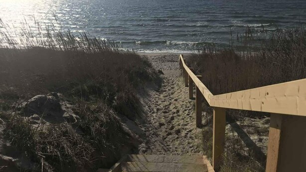 Una escalera de madera que conduce a una playa con vistas al océano.