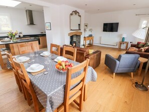 Un coin repas avec une table dressée pour quatre personnes, une cheminée, un téléviseur et un canapé dans un salon.