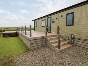 A caravan with a wooden deck, a set of stairs, and a gravel ground. - Ramsey, Little Haven (Haverfordwest)