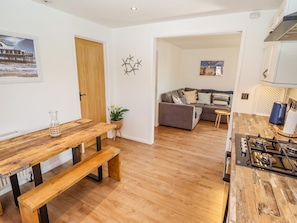 Una sala de estar con una mesa de comedor de madera, un sofá y una cocina con estufa.